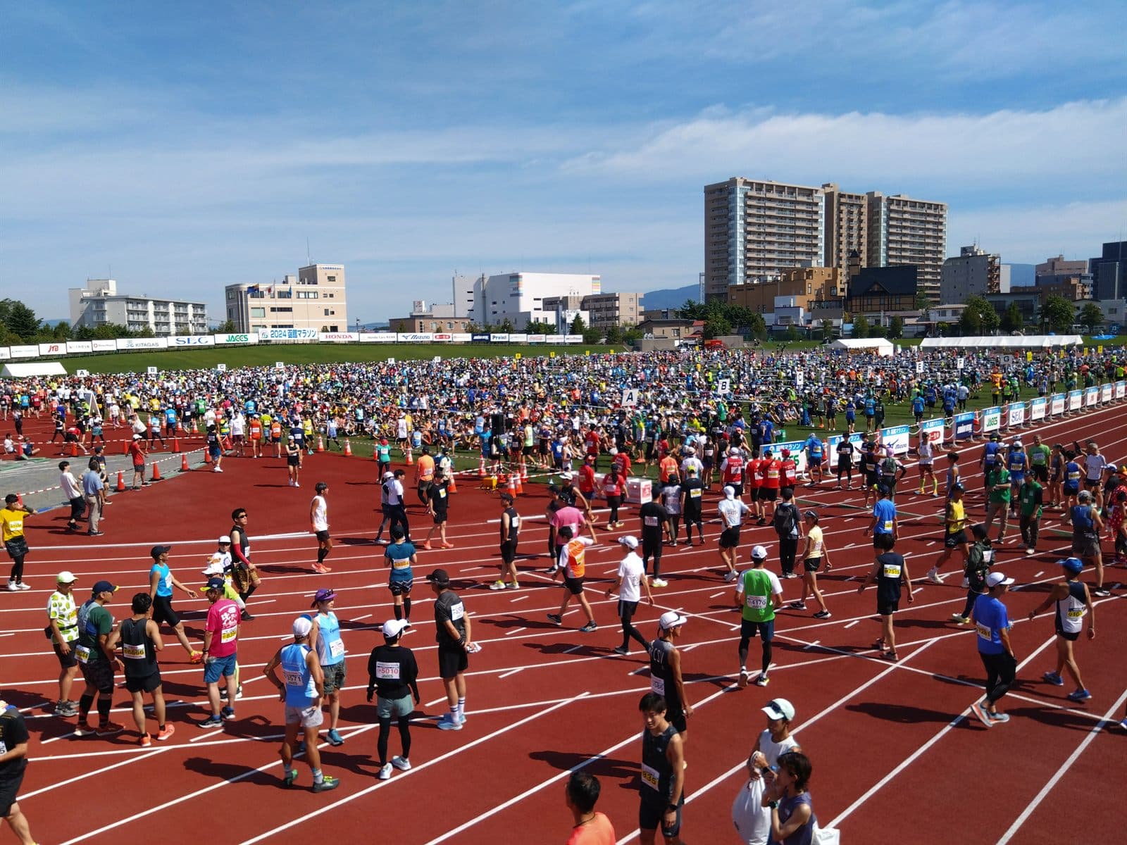 千代台公園陸上競技場のトラックに整列する函館マラソンのランナー